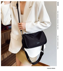 Détail du sac bandoulière noir en nylon avec large sangle et logo métallique élégant