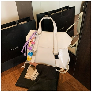 Close-up of white leather bucket bag with decorative colorful charms and metal buckles