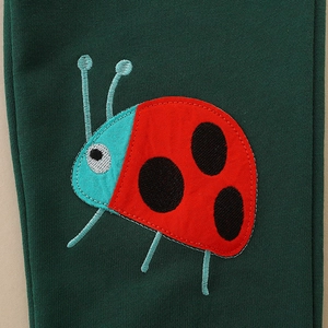 Kids dark green joggers with detailed red and blue ladybug embroidery on the leg