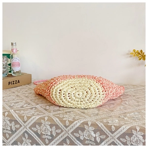 Detailed view of handmade floral straw bag with pink spiral crochet base on lace