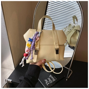 Detail of cream leather backpack featuring silver buckles and colorful letter charms