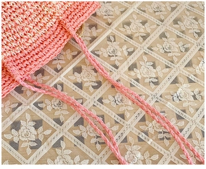 Detailed view of the pink hand-woven straw bag with intricate crochet textures and straps