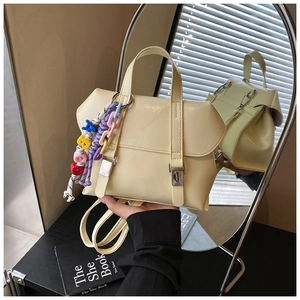 Close-up of light beige backpack featuring decorative metal buckles and alphabet charms