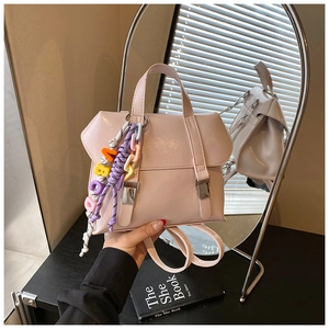Detailed view of light pink versatile bucket bag with rainbow letter charm on black desk