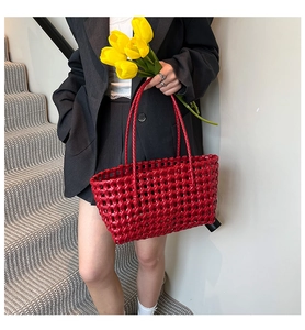 Detail of a bright red woven tote bag featuring a glossy hollow weave pattern for beach fashion