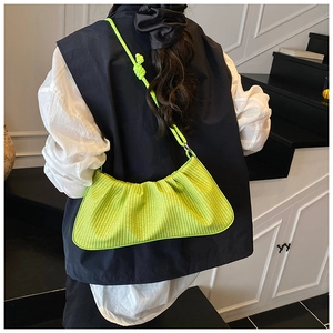 Close-up of neon green woven bag featuring knot strap detail on model's shoulder