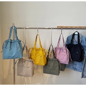 Close-up of drawstring tote bags in six colors with front buckle pockets and nylon texture