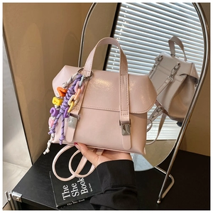 Detail of light pink mini backpack with silver buckle and colorful letter charm accessory