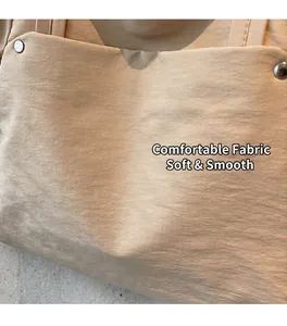 Gros plan sur la texture du tissu crème et les rivets métalliques d'un sac cabas