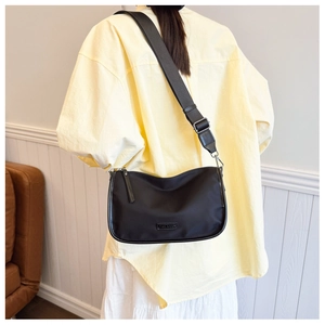 Détail d'un sac bandoulière en nylon noir avec large sangle porté par un mannequin