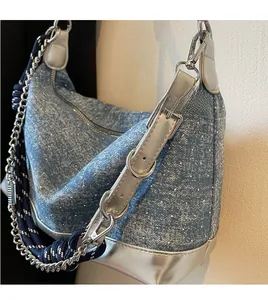 Detail of blue denim tote bag with silver metallic trim and multi-strap design detail