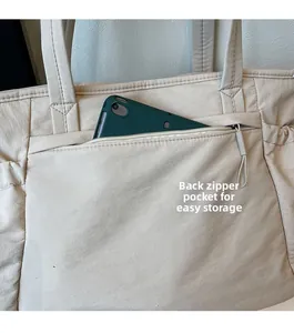 Détail de la poche zippée arrière d'un sac cabas beige avec une tablette verte
