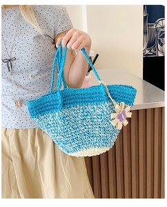 Detail of blue gradient straw tote bag with handmade knit flower charm and woven handle