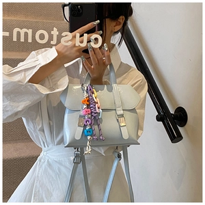 Detail of light blue leather handbag with decorative straps and rainbow letter charm