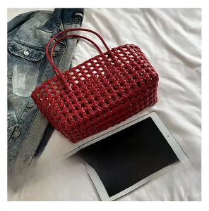 Detail of red hollow woven beach bag with thin handles on white bedding backdrop