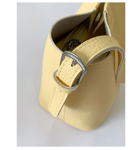 Detail of silver metal buckle and zipper closure on yellow lychee leather handbag