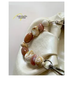 Close-up of detachable resin bead handle with marble texture on cream pleated bucket bag