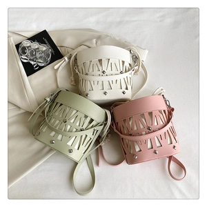 Three hollow bucket bags in cream, pink and sage green colors with laser cutouts