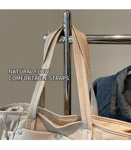 Détail des larges bandoulières renforcées et des coutures sur un sac cabas beige minimaliste