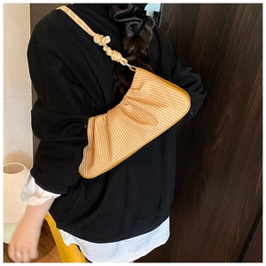 Detail of yellow ruched woven hobo bag with thick knotted shoulder strap on model