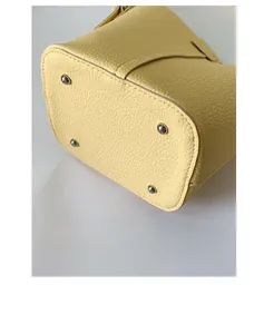 Close-up of light yellow lychee grain leather bucket bag base with silver metal feet