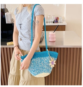 Close-up of blue and white crochet straw tote bag with floral pendant and shoulder strap