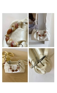 Detail of cream pleated bucket bag with marble beads handle and silver hardware