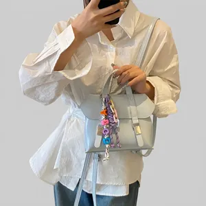 Detail of light blue casual backpack featuring decorative metal buckles and letter charms