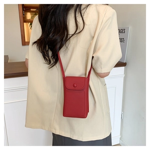 Detail of red litchi texture leather mini crossbody bag with a round flap buckle