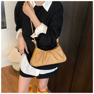 Detail shot of yellow pleated woven shoulder bag with fine fiber texture and leather edges