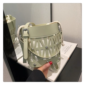 Detail of light green bucket bag featuring hollowed-out geometric pattern and silver studs