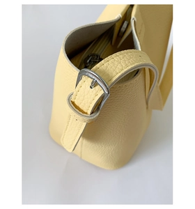 Close-up of light yellow lychee pattern leather bucket bag with silver buckle and magnetic clasp
