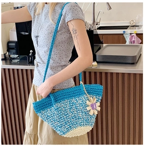 Detail of hand-woven tote bag showing blue gradient patterns and a sunflower pendant
