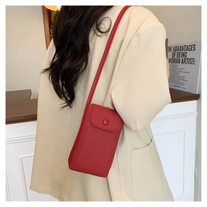 Detail view of a bright red lychee leather mini crossbody phone bag worn by a model