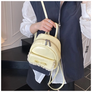 Detail eines cremegelben Mini-Rucksacks mit Spitzenbesatz und süßer Schleifenkante