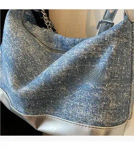 Detail of blue denim shoulder bag with silver studs and metallic leather trim