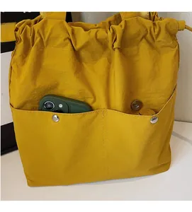 Detail of a bright yellow nylon bucket bag showing front pockets for smartphone storage