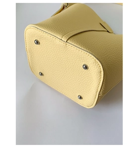 Detail of light yellow pebble leather bucket bag base with silver anti-wear metal feet