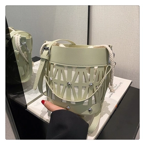 Detail of light green hollow-out bucket bag with silver studs and canvas inner pouch