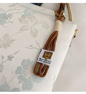 Close-up of jacquard floral handbag with bamboo handle and gold chain details
