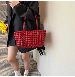 Close-up of bright red woven hollow-out beach tote bag with structured mesh patterns