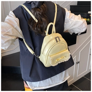 Detail eines creme-minirucksacks mit Schleife und Spitze am Modell für den Größenvergleich