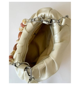 Macro detail of creamy white pleated cloud bag with marble resin chain and zipper