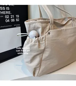 Détail d'un sac cabas beige avec une poche latérale à cordon pratique pour parapluie