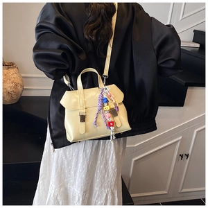 Detail of beige faux leather bucket bag featuring colorful beaded charm and silver buckle