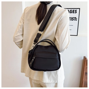 Rear view of model wearing minimalist black crossbody bag with adjustable wide fabric strap