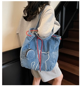 Blue denim tote bag detail featuring white cat embroidery and red rope shoulder strap
