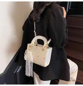 Detail of white PU leather handbag with orange daisy embroidery and lace bow accessory