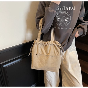 Detail of light beige tote bag featuring drawstring closure and large metal button pockets
