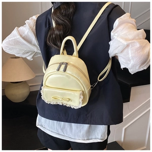 Detailansicht eines gelben Mini-Rucksacks mit Schleife und Spitze auf blauem Hemd